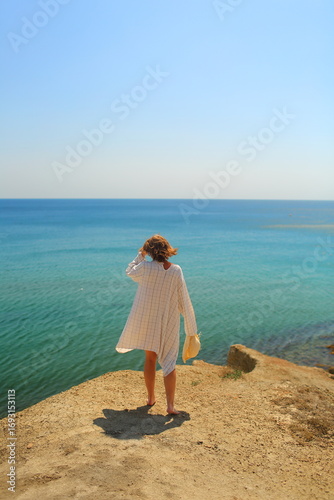 a girl with flowing hair stands by the blue sea on the yellow shore, inspired by the wind
