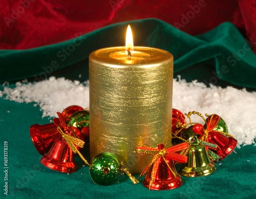 Golden candle surrounded by Christmas bells and snow on green velvet