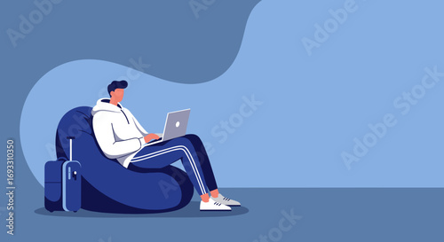 Young man working remotely on a laptop, comfortably seated on a beanbag with a suitcase nearby, symbolizing modern flexible work, travel, and digital nomad lifestyle.