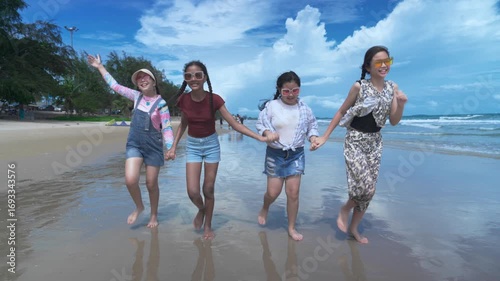 Four Asian girls are having fun playing in the sea on a sunny day. They are splashing around and holding hands. It's the perfect picture of friendship, fun, and relaxation.