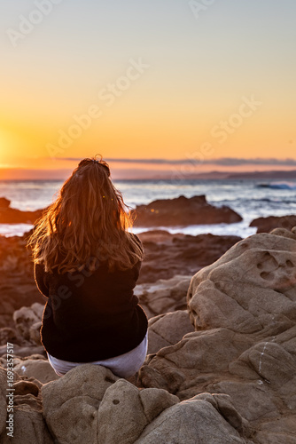 view of woman looking out on the beach at sunset