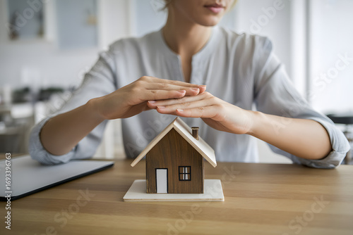 Home Security: A person shields a miniature house, symbolizing the concepts of protection, safety, and security.
