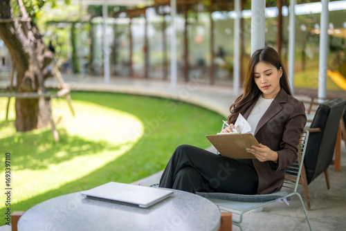 Businesswoman working with documents and laptop in outdoor office space