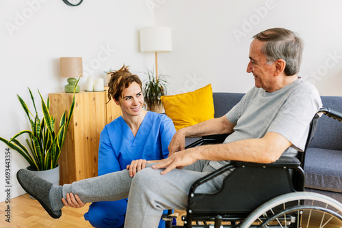 Wallpaper Mural Smiling nurse assisting a happy senior man in a wheelchair with leg exercises in a home healthcare setting Torontodigital.ca