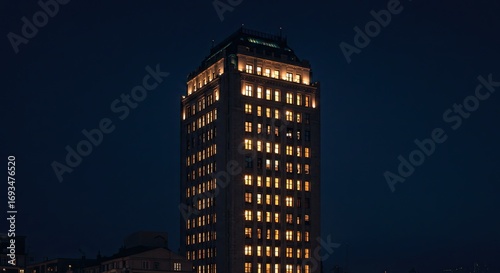 Tall Concrete Building Glowing with Golden Windows at Night