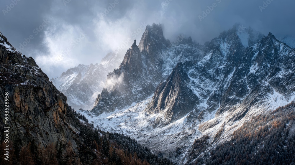 Fototapeta premium Majestic snow-capped mountain range rising through misty clouds with dramatic peaks and breathtaking panoramic view of alpine wilderness in tranquil natural landscape
