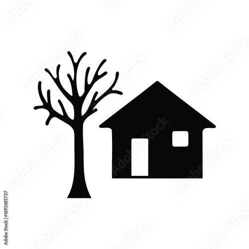 Silhouette of a house next to a bare tree in stark contrast