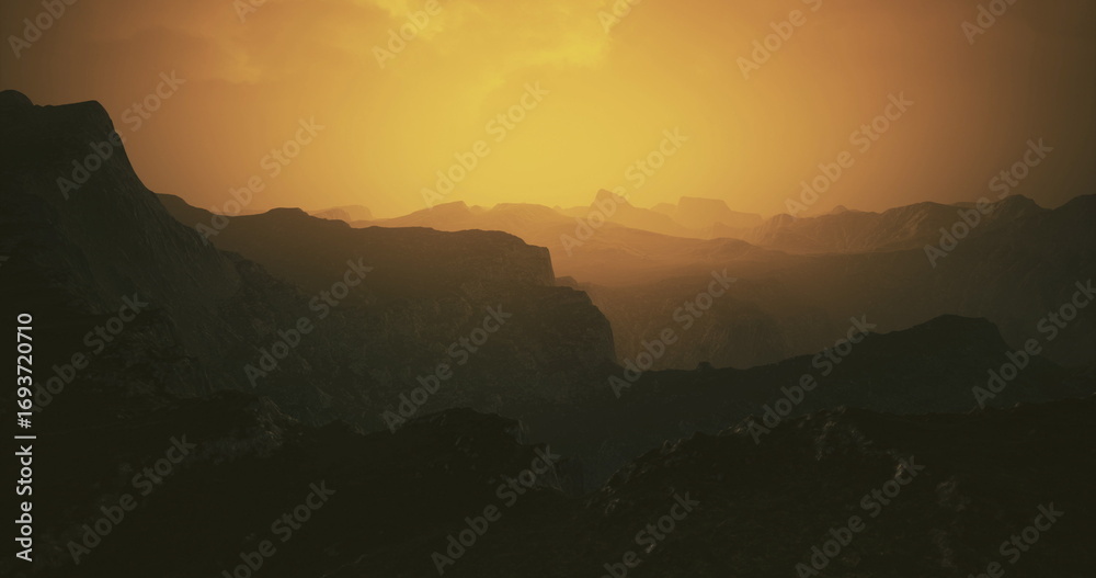 Obraz premium A breathtaking view of rugged mountains illuminated by the warm glow of sunset. The landscape features deep valleys and silhouettes against the vibrant sky, creating a serene atmosphere.
