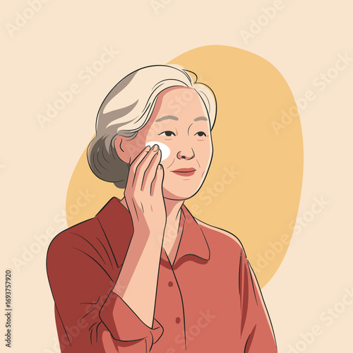 An older woman gently applies a skincare product to her cheek using a cotton pad. She has gray hair and is in a simple, bright environment.