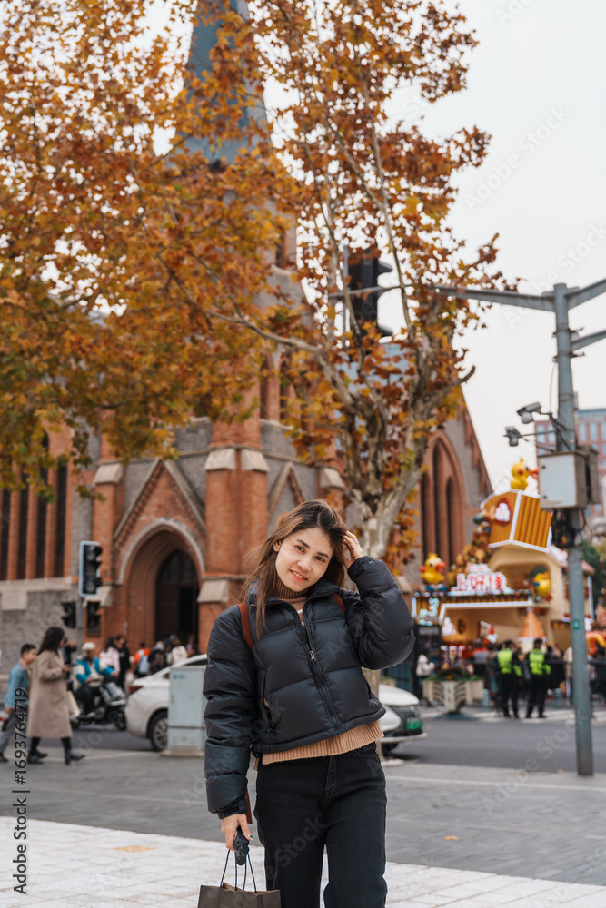 Obraz premium woman traveler visiting in Shanghai, China. Happy Female Tourist sightseeing Shanghai Union Church view in autumn season. landmark and popular for tourism attractions. Travel and vacation