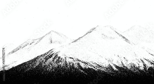 High-contrast black and white photograph of snow-covered mountain peaks with dark forested bases against a bright sky.