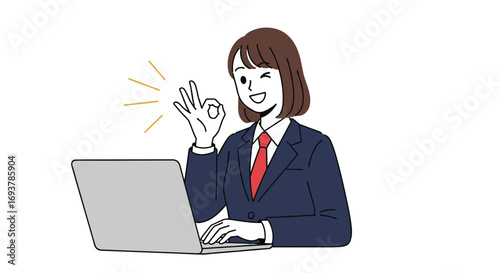 Young woman in business suit working on laptop gives okay gesture with smiling face