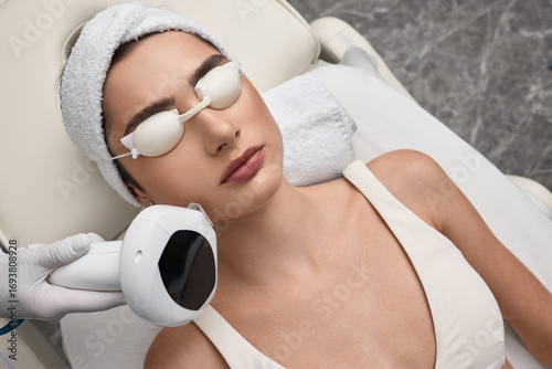 Foto Female patient while photorejuvenation procedure with intense pulsed light IPL a
