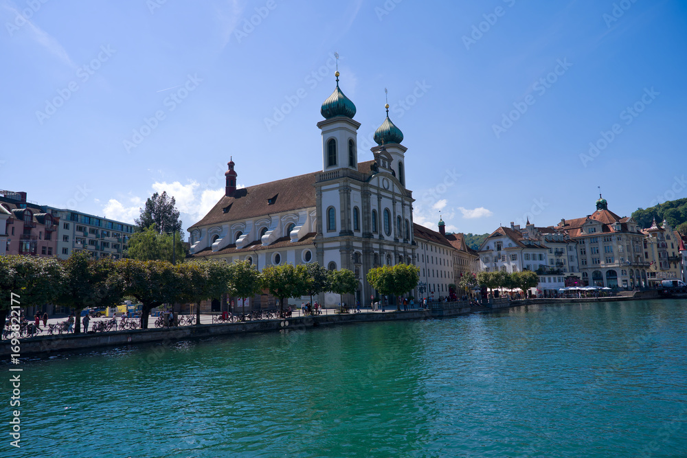 Fototapeta premium Scenic view of Reuss River and Jesuit Church at Swiss city of Luzern on a sunny summer day. Photo taken August 25th, 2025, Lucerne, Switzerland.