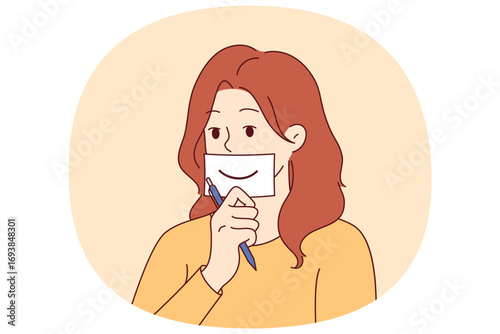 Woman shows fake smile, symbolizing happiness, by placing piece of paper with drawn mouth on face. Concept of fake happiness and desire to demonstrate success in life, hiding depressive state