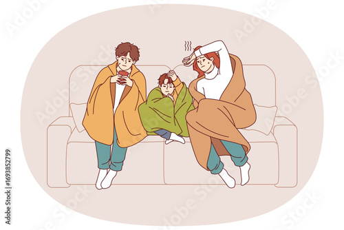 Caught cold family sits on sofa wrapped in blanket and drinks hot tea trying to get rid of virus. Caught cold couple with child contracted infection causing fever and chills and needs medication