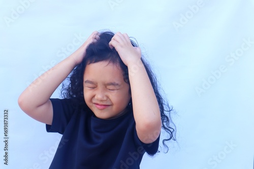 Asian girl scratching head, because scalp is itchy or there are head lice, isolated on white background.