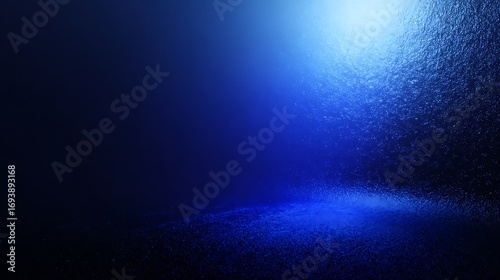 A dark, textured room illuminated by a bright, cool blue light emanating from above, creating a dramatic and atmospheric spotlight effect