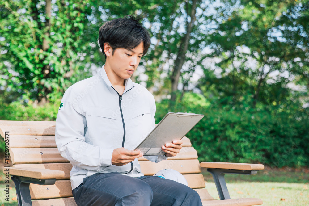 Fototapeta premium 作業着の男性が資料をチェックする A man in work clothes checks documents
