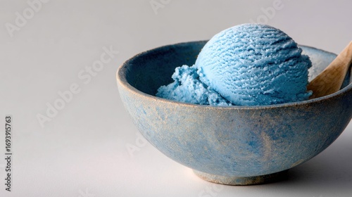 Blue bowl with a scoop of ice cream in it. the ice cream is a light blue color and appears to be freshly made. the bowl is made of ceramic and has a smooth texture.