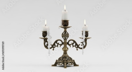 Ornate bronze candelabra holding three lit white candles, with dripping wax on a plain backdrop