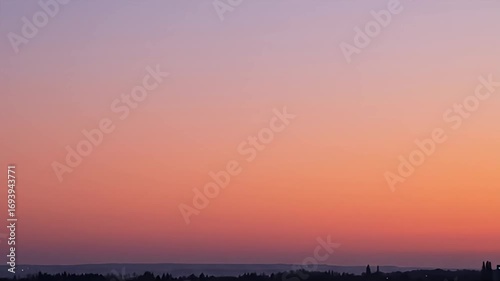 Gradient sky over the horizon, with subtle silhouette of trees & distant buildings