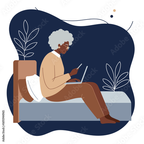 Elderly Black woman comfortably using a laptop and smartphone on her bed, illustrating remote work, communication, or modern digital lifestyle at home.