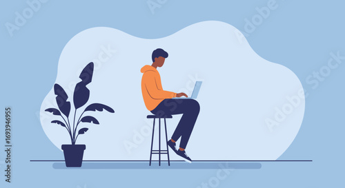 A young man in a hoodie works on his laptop, sitting on a stool with a plant nearby. Represents remote work, freelance, or online learning. Modern lifestyle and productivity concept.