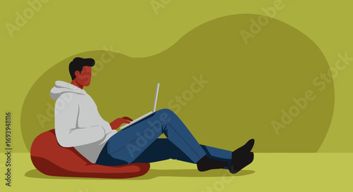 Young man working or studying remotely on a laptop while relaxing comfortably on a beanbag chair in a modern, casual home environment. Ideal for themes of productivity and modern lifestyle.