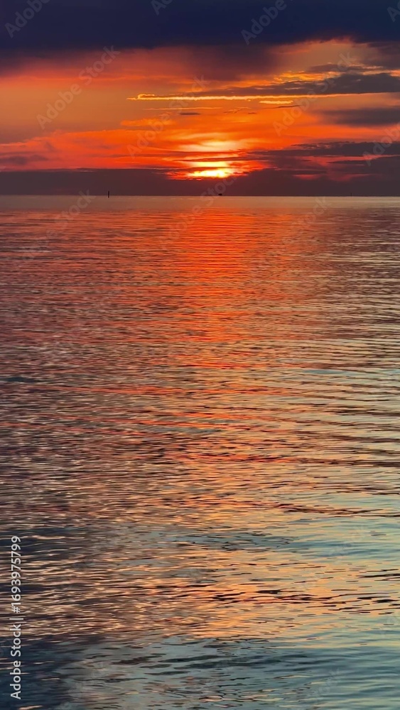 Obraz premium Sunset sky reflecting in the Baltic sea, view from the sandy shore in Sweden.