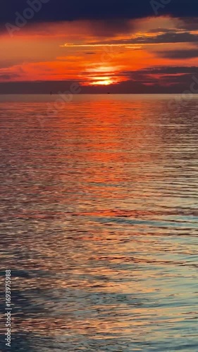 Sunset sky reflecting in the Baltic sea, view from the sandy shore in Sweden.