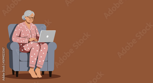 Happy senior woman in pajamas sits comfortably in an armchair, engaging with her laptop. Represents modern elderly, remote work, or online connection.