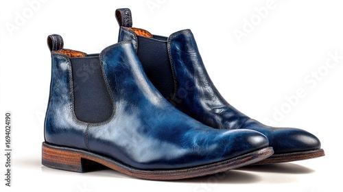 Two blue leather Chelsea boots are positioned on a white surface