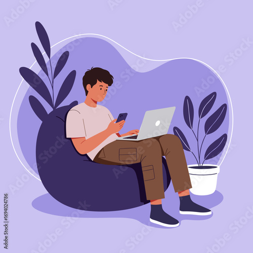 Young man comfortably working remotely on a bean bag, multitasking with laptop and smartphone. Ideal for themes of freelance, online education, and modern lifestyle.