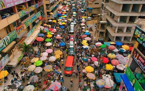 Accra, Ghana - 23 March 2024: Aerial view of Makola Market pulsates with life, a vibrant tapestry of colorful umbrellas shading bustling crowds and vehicles amidst the urban architecture.
