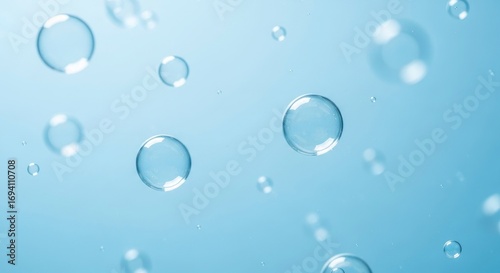 Transparent spherical bubbles of varying sizes float against a soft blue background Some bubbles are sharply defined showing clear reflections while others are gently blurred