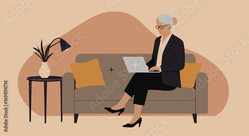 Professional senior woman productively working on her laptop from a modern sofa. Represents remote work, an active lifestyle, and embracing technology.