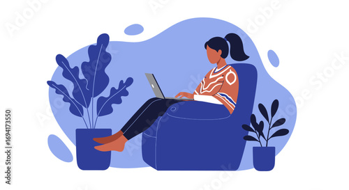 Young woman comfortably works on her laptop from a cozy armchair at home. Ideal for remote work, freelancing, and digital lifestyle concepts.