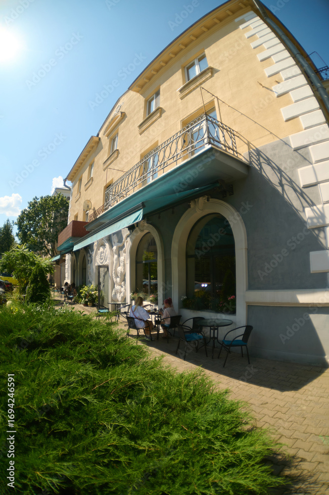 Naklejka premium Outdoor cafe seating next to classic urban building