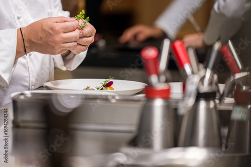 Foto Gros plan sur les mains d’un chef étoilé en train de finaliser le dressage d’un plat gastronomique dans sa cuisine