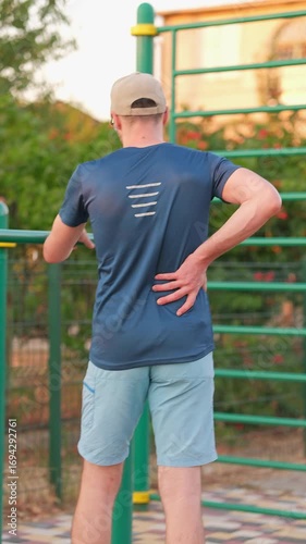 Man holding his back in pain after a workout, concept of trauma or pulled muscle during exercise.