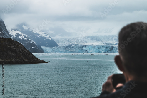 Close up view on the glaciers in Alaska, mountains and glacier landscape. Man taking photo of the glacier