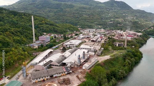 industrial zone of Brod Foča Zubovići in Bosnia and Herzegovina moving over industrial buildings with green forest surrounding the area and a river on the right
