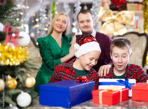 Smiling family celebrating Christmas and giving each other gifts