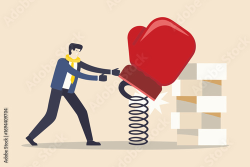 Businessman using a boxing glove on a spring to knock down a tower of blocks representing challenges