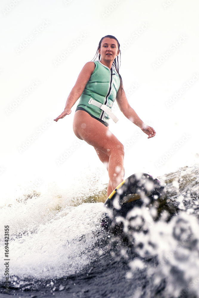 Fototapeta premium Young woman wakeboarding on a lake during a sunny day