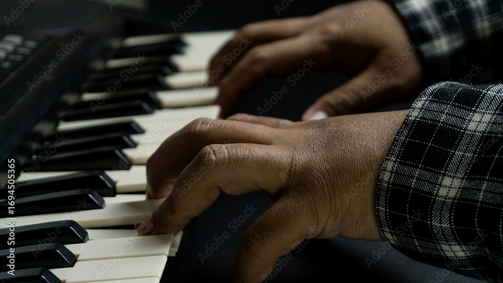 Fototapeta premium Pianist hands playing with both hands viewed from diagonal top angle, black piano with dark background, concept of concert, melody, art, and expressive performance.