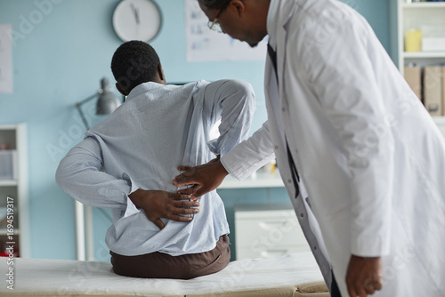 Cuadro en lienzo Black young adult man sitting on examination table holding lower back while Blac
