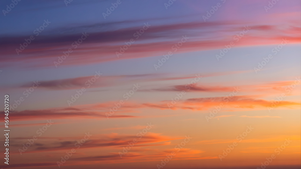 Obraz premium Vibrant sunset sky with wispy clouds painting the horizon in warm hues
