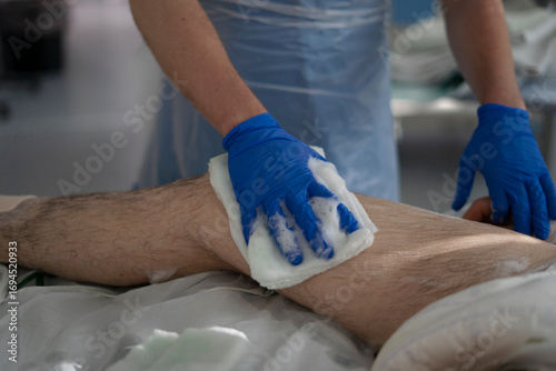 Foto Nurse cleaning patient's leg with antiseptic solution before surgery